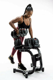 Woman lifting an adjustable dumbbell from a Blast weight rack