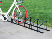 Black metal bicycle parking rack installed on a sidewalk next to a white bike.