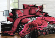 Red rose print bedding set with matching pillows on a bed in a modern bedroom.
