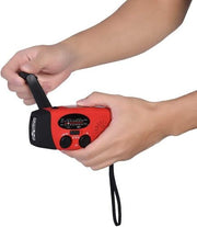 Hand holding a compact red emergency hand-crank radio with a built-in flashlight