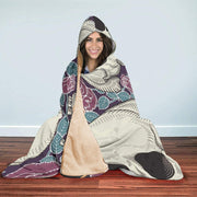 Smiling woman wrapped in a floral patterned hooded blanket with a soft beige lining.