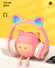 Pink cat ear glowing LED headphones with a cute pink character figure on a white surface.