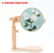 Wooden embroidery hoop stand holding a floral needlework design on light blue fabric