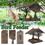 Decorative wooden bird feeder with tree design attracting small birds in a garden setting.
