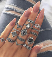 Hand adorned with multiple vintage-style silver bohemian rings and gemstone accessories.